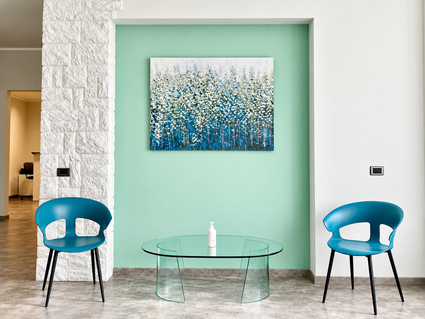 Area di accoglienza dello Studio Medico Calliope: sedute nei toni del teal e tavolino in vetro accanto a una parete verde acqua con opera d'arte botanica